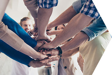 Emplyees gathered together with hands on top of each other's