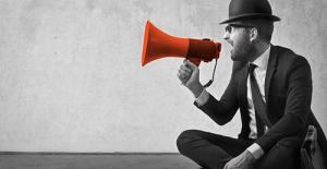 Man in black and white speaking into a red megaphone