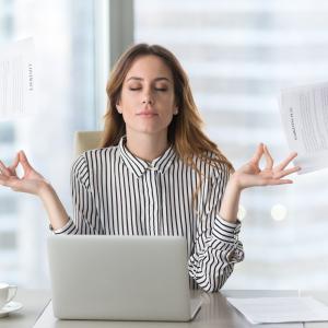 Lady doing balance gesture with hands behind computer