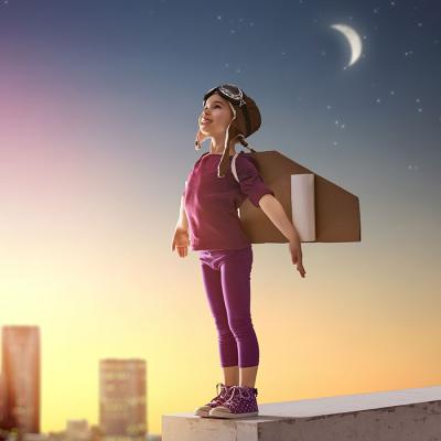 Young child dressed as superhero with paper wings ready for takeoff