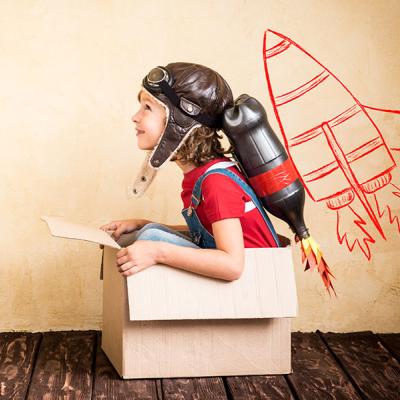 Child riding pretend cardboard rocket