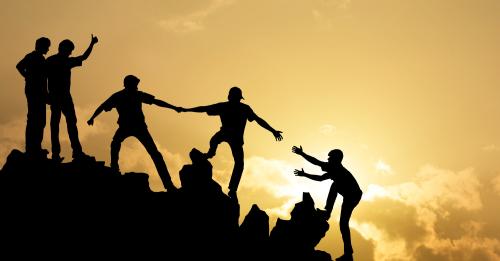 Group of hikers helping each other up a hill