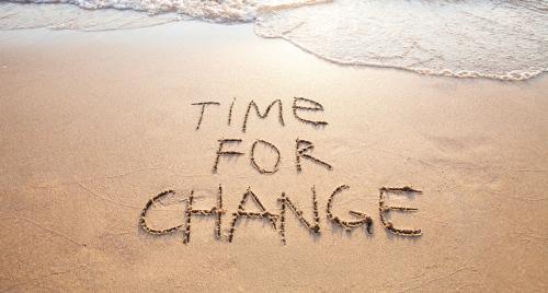 Time for a change written on sand at beach