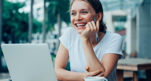 Woman having coffee at desk with laptop