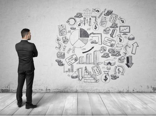 Man standing up with arms crossed looking at various business icons