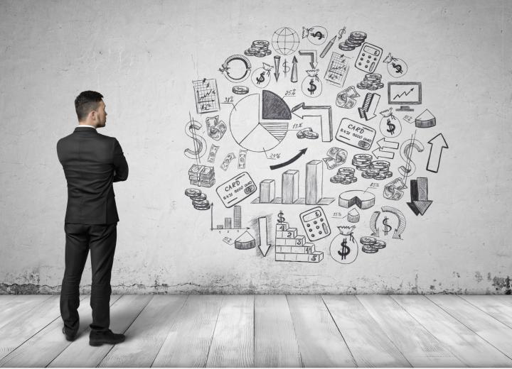 Man standing up with arms crossed looking at various business icons