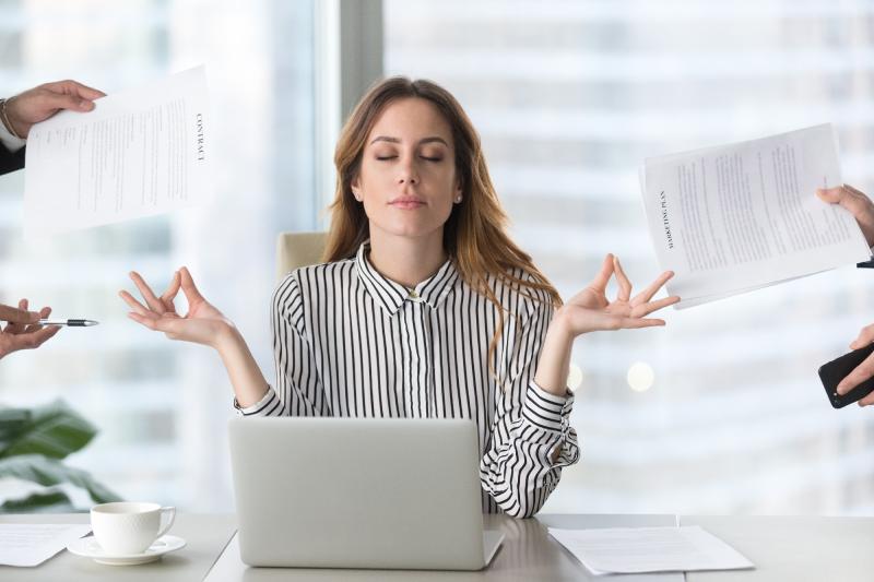 Lady doing balance gesture with hands behind computer