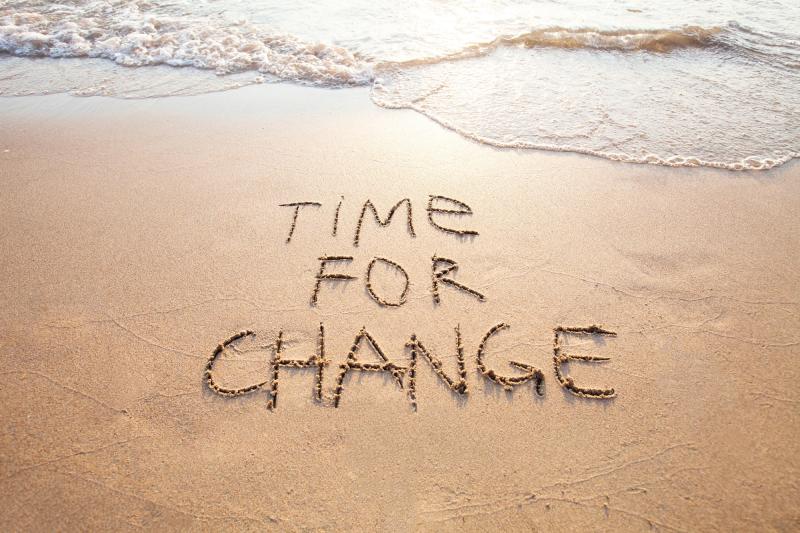 Time for a change written on sand at beach