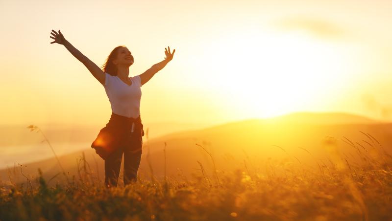 Woman with arms outstretched at sunset