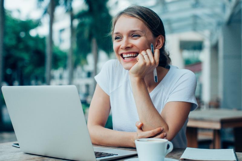 Woman having coffee at desk with laptop